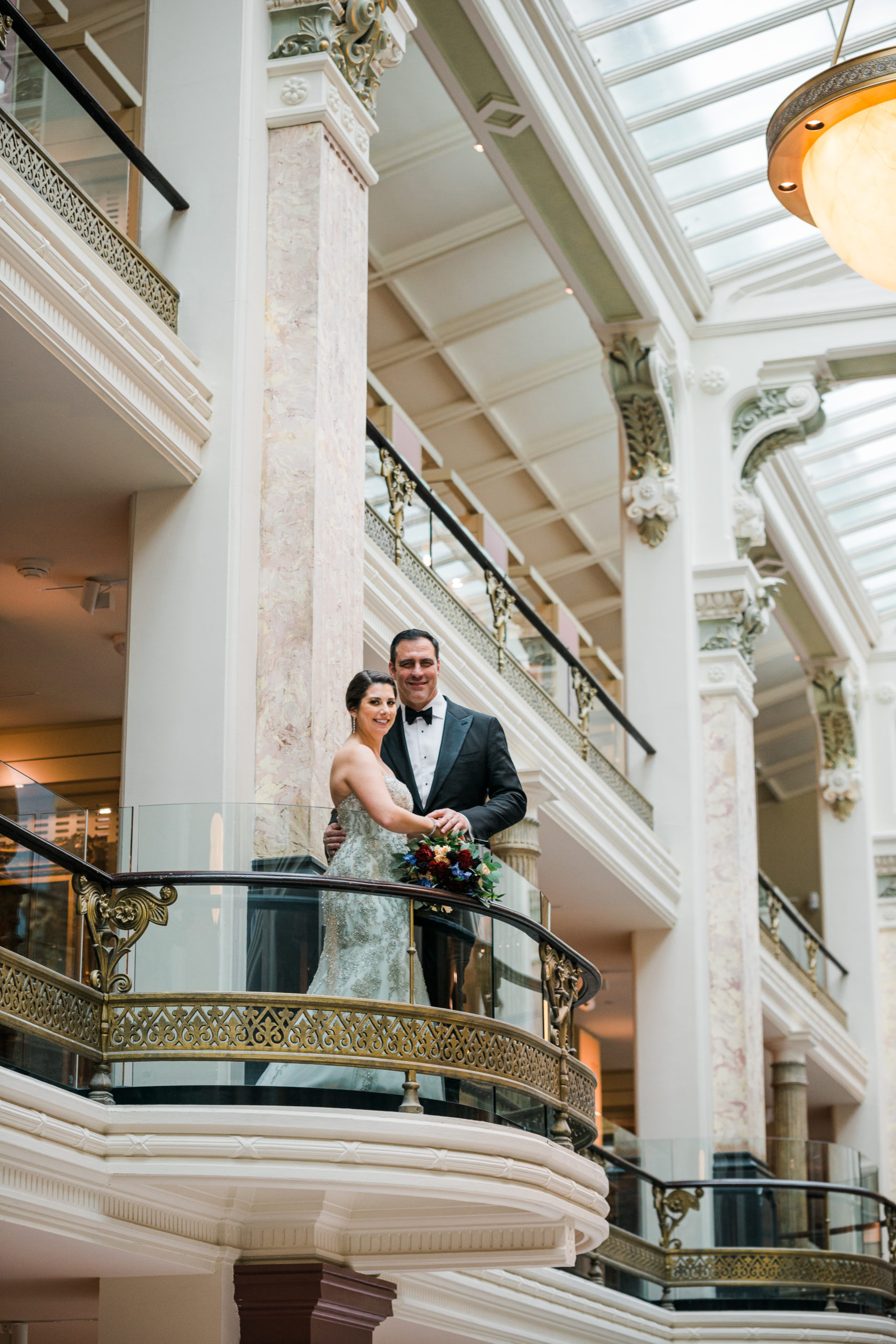 The bride and groom posing on a balcony at the Marriot Marquis hotel in Washington DC