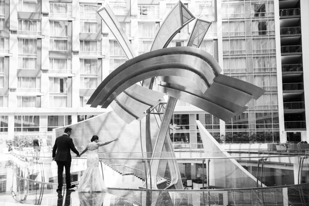 A black and white picture of the bride and groom looking at a sculpture at the Marriot Marquis hotel in Washington DC