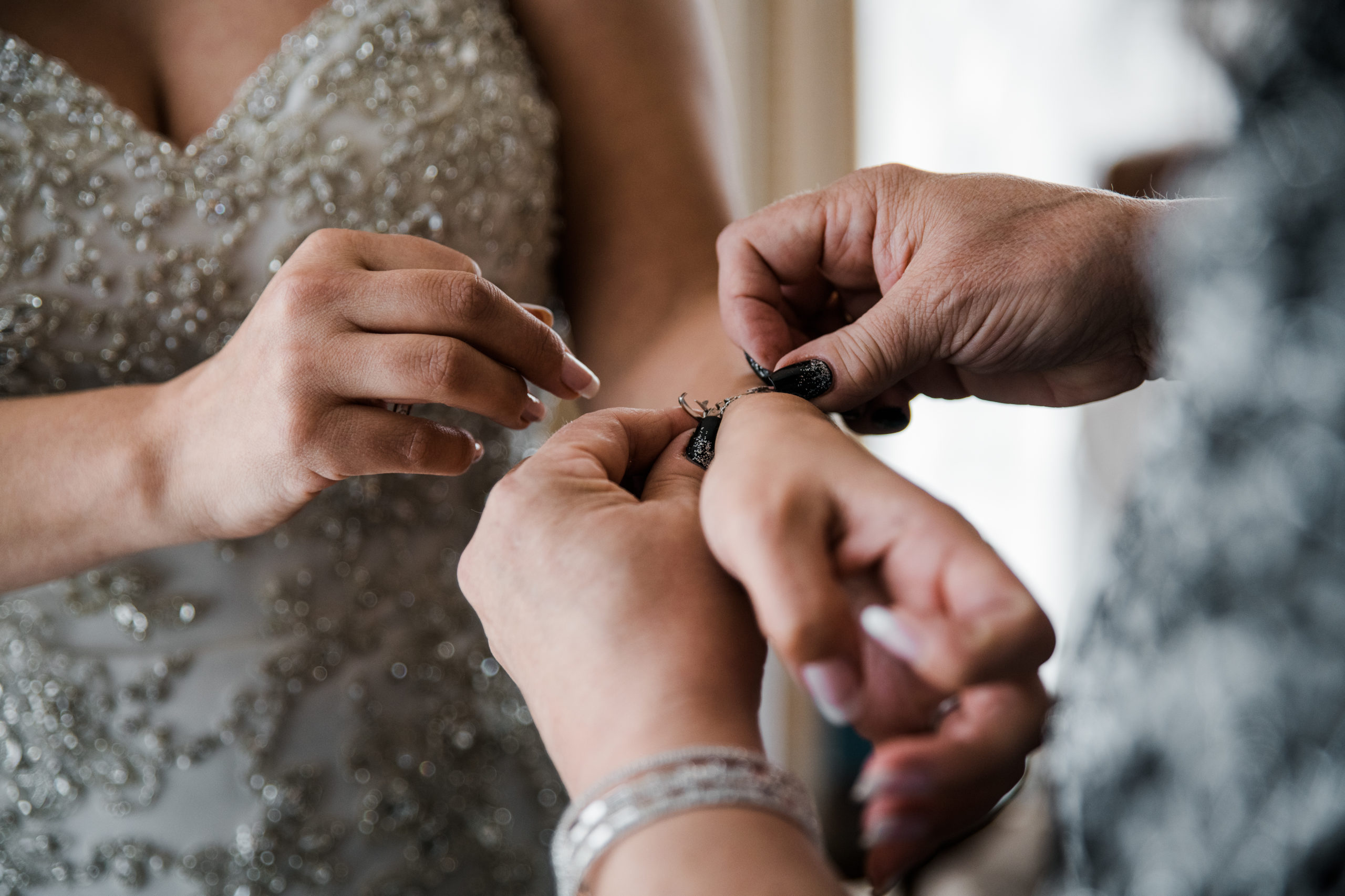 Close up of hands putting a bracelet on the bride's wrist.