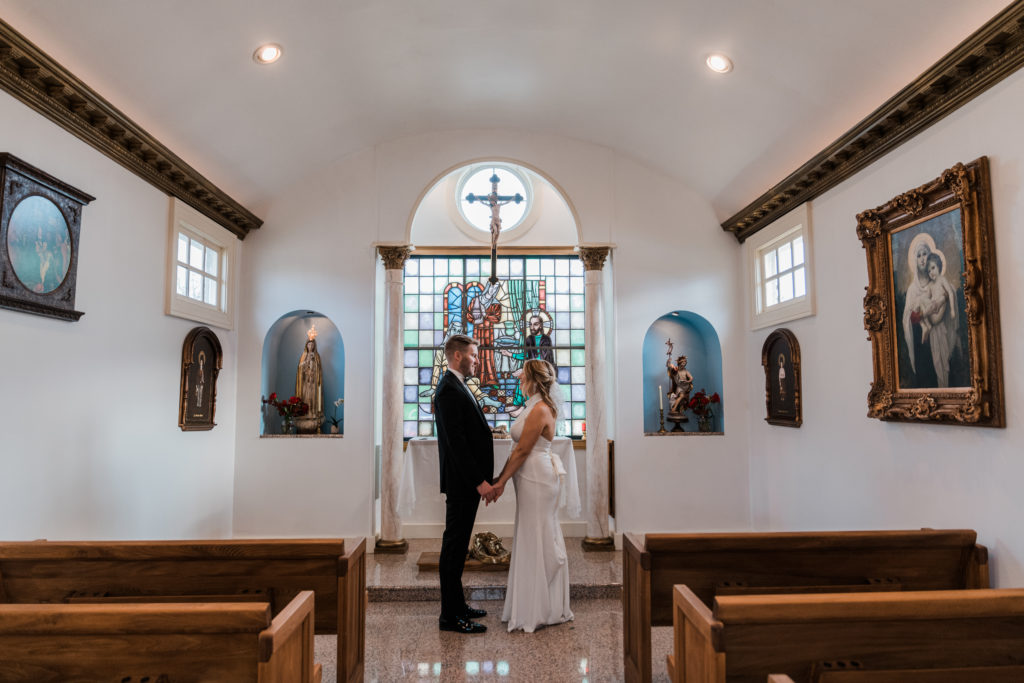 A bride and groom holding hands in front of an altar 