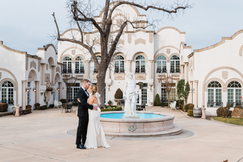 A bride and groom kissing in front of a fountain at Morais Vineyards and Winery
