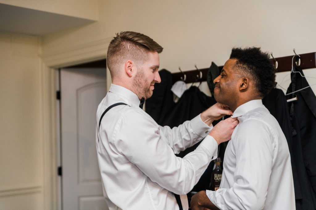 A groomsman helping another groomsman with his tie at Morais Vineyards and Winery