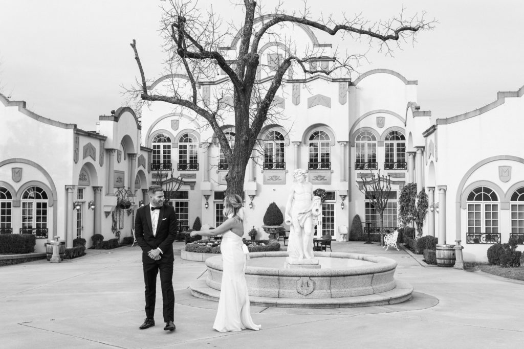 A bride and groom doing a first look in front of a fountain at Morais Vineyards and Winery