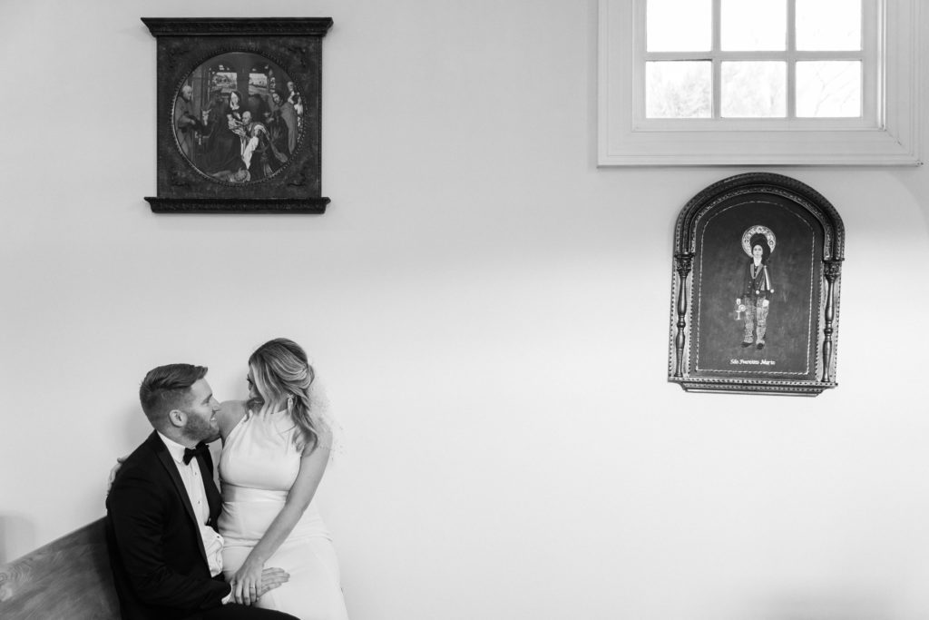 A bride and groom sitting and looking at one another in a rom at Morais Vineyards and Winery