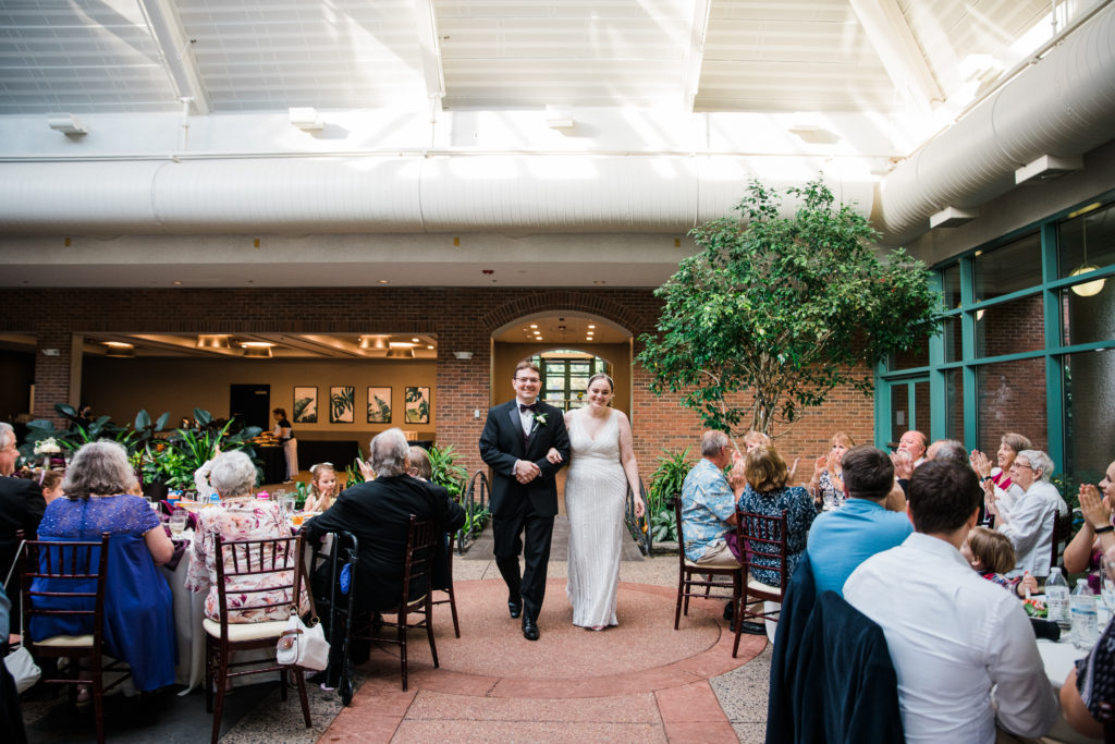 Bride and groom walking into a wedding reception at the Atrium at Meadowlark Botanical Gardens