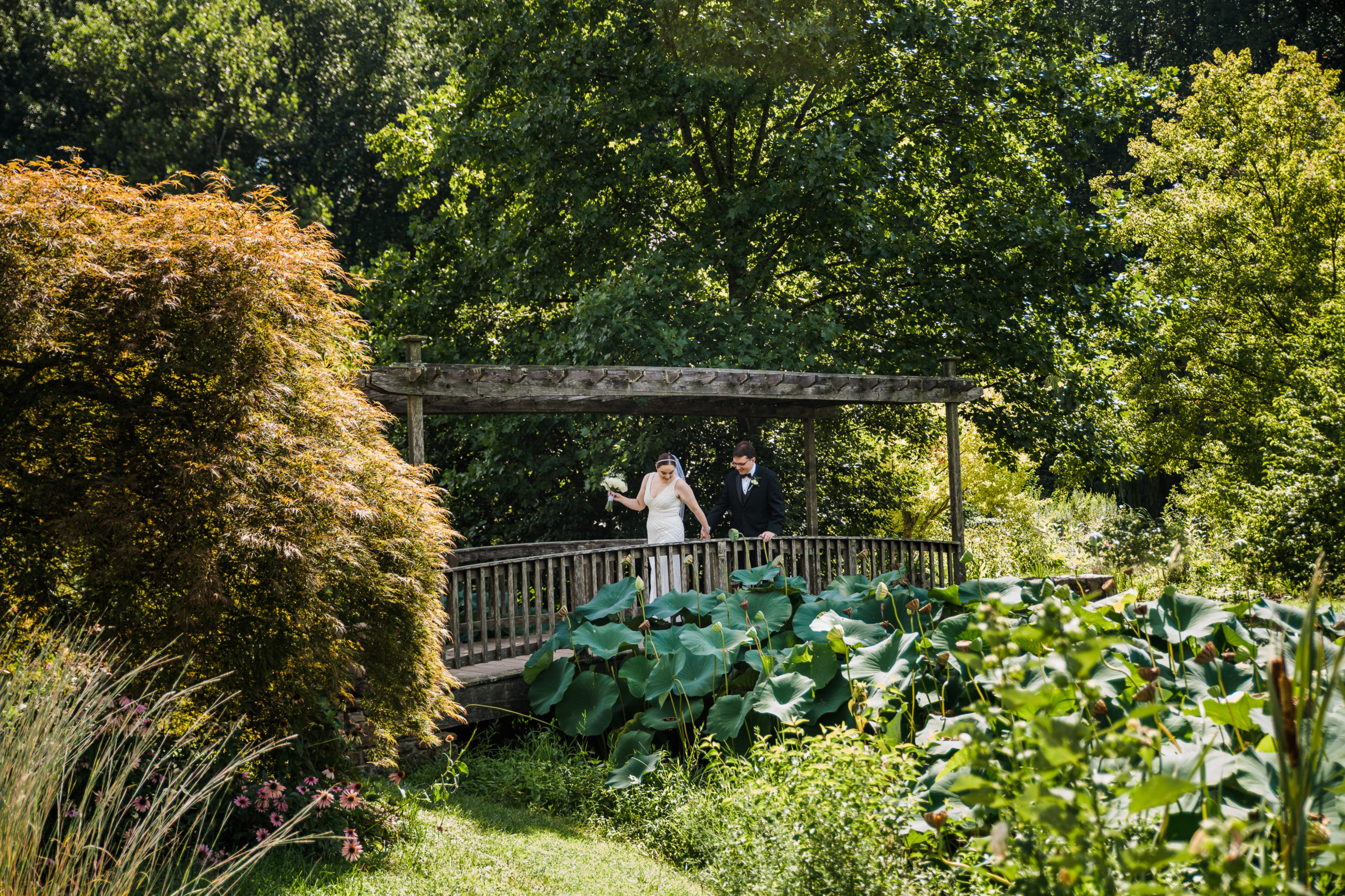 Bride and groom standing on a bridge at the Atrium at Meadowlark Botanical Gardens