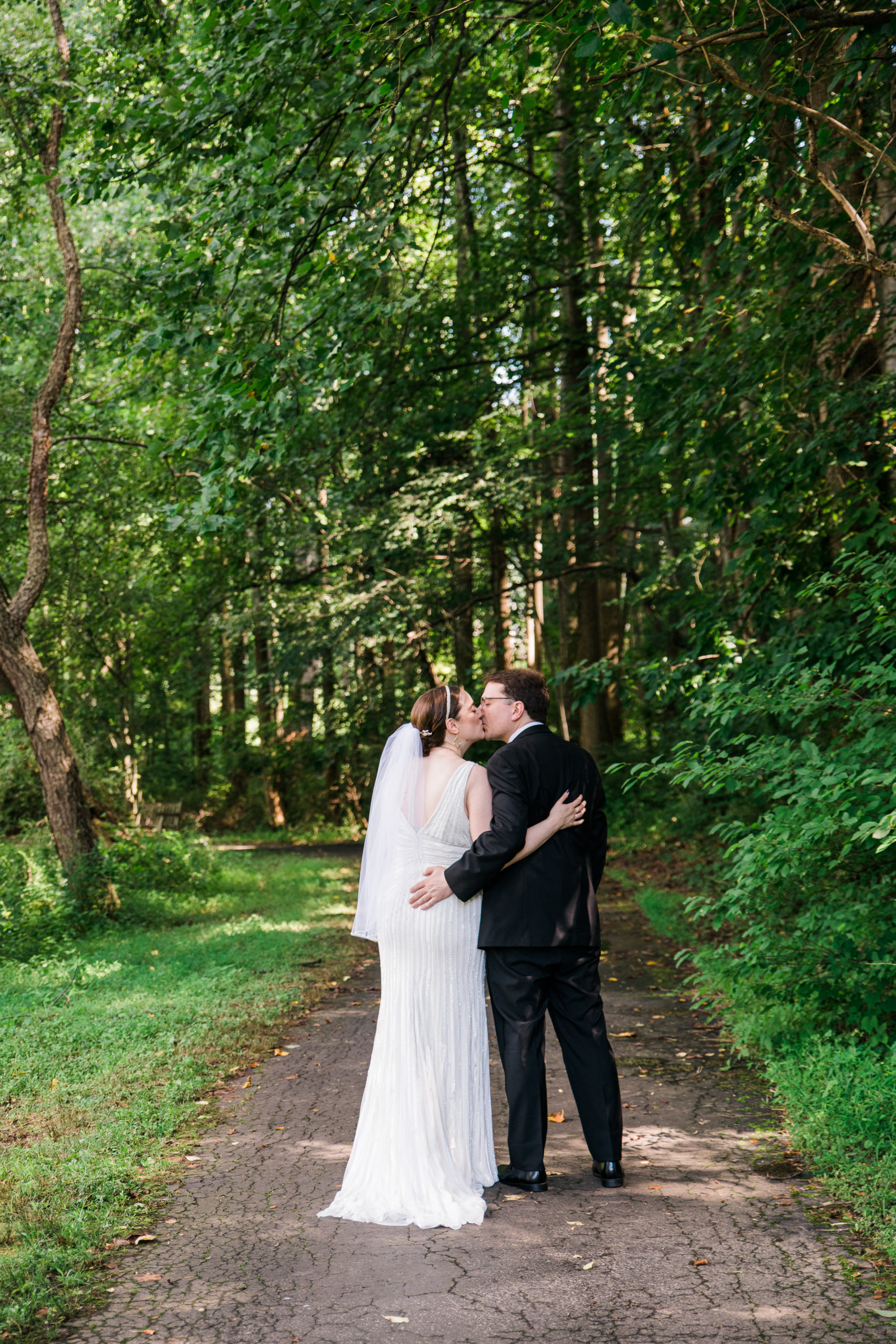 Bride and groom kissing in front of a forest at the Atrium at Meadowlark at Botanical Gardens