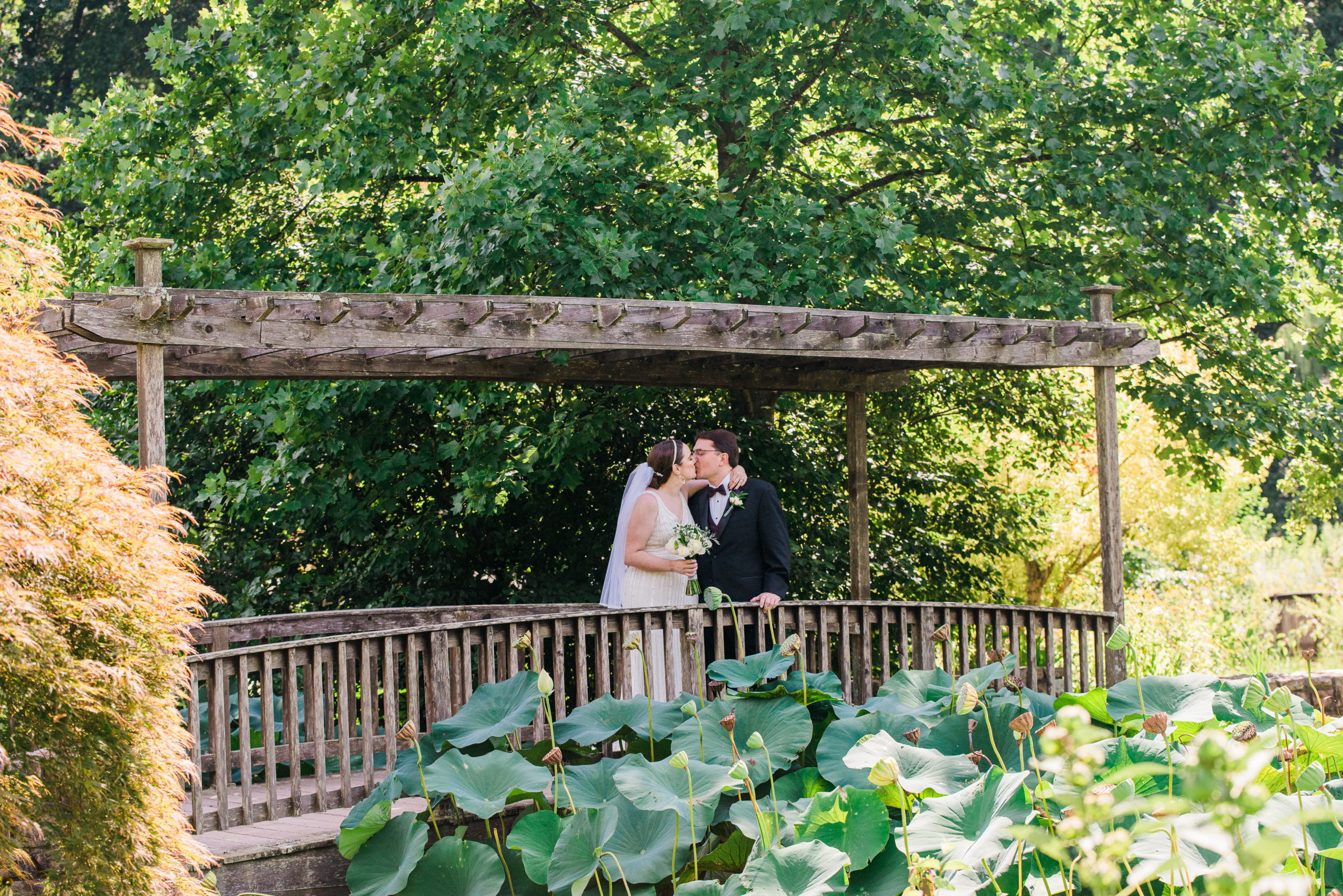 Bride and groom kissing on a bridge at the Atrium at Meadowlark Botanical Gardens