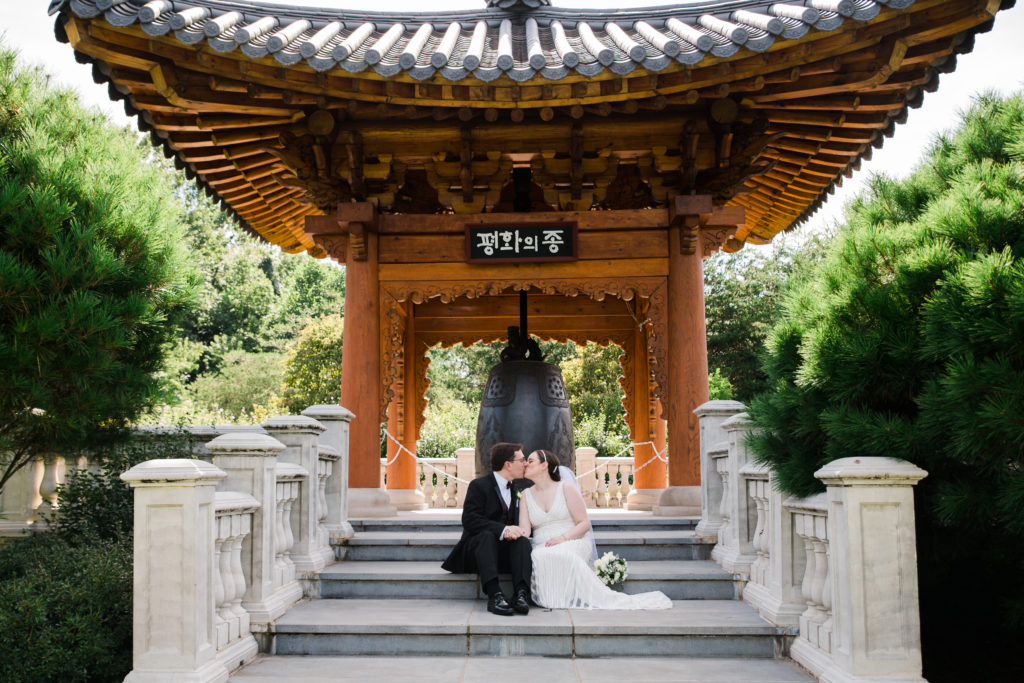 Bride and groom kissing on the steps of the Korean Bell Garden at the Atrium at Meadowlark Botanical Gardens