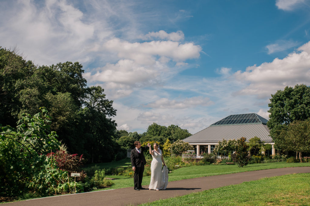 Bride and groom walking through a garden at the Atrium at Meadowlark Botanical Gardens