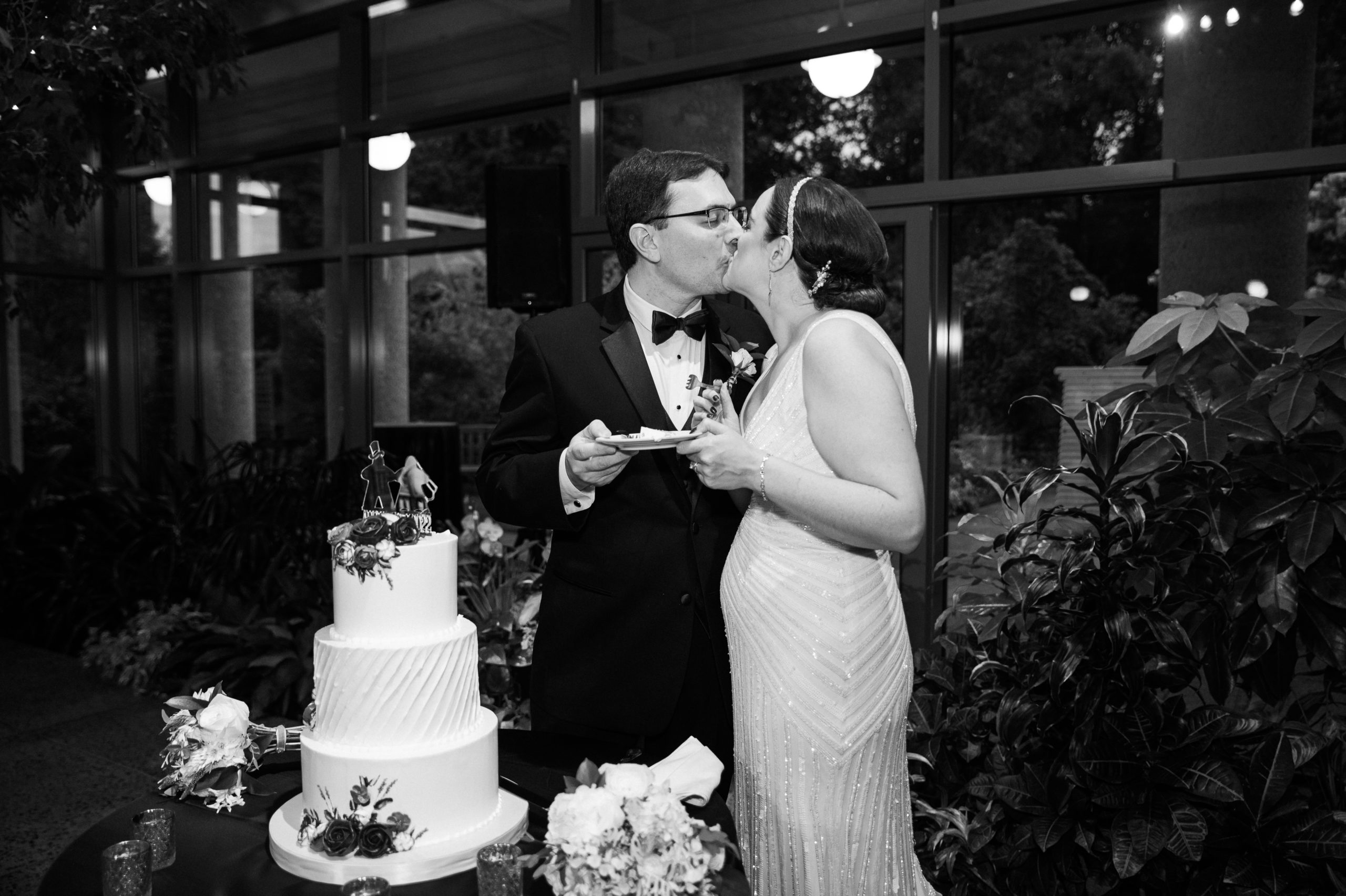 Bride and groom kissing after cutting the wedding cake at the Atrium at Meadowlark Botanical Gardens