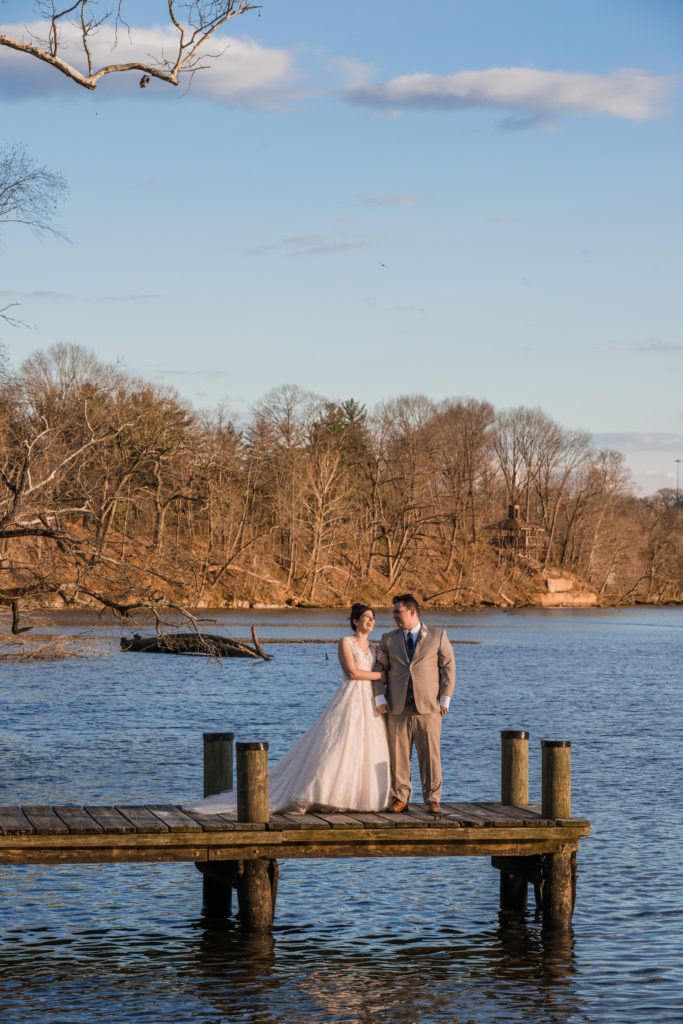Bride and groom standing on a dock with water around them at the River View at Occoquan