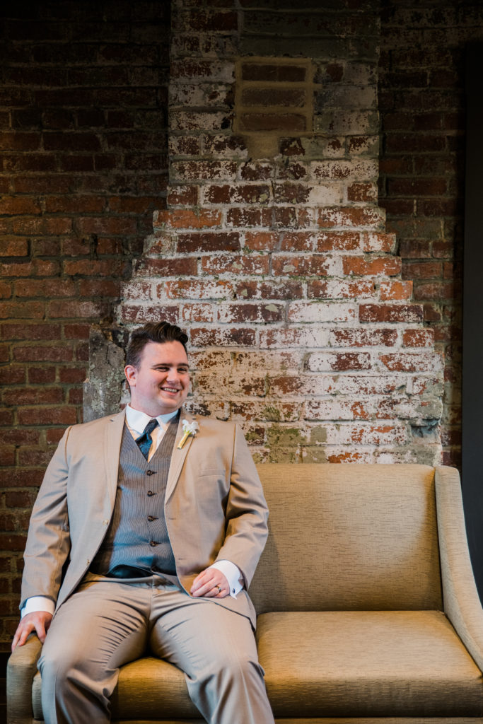Groom sitting on a couch and smiling before his wedding