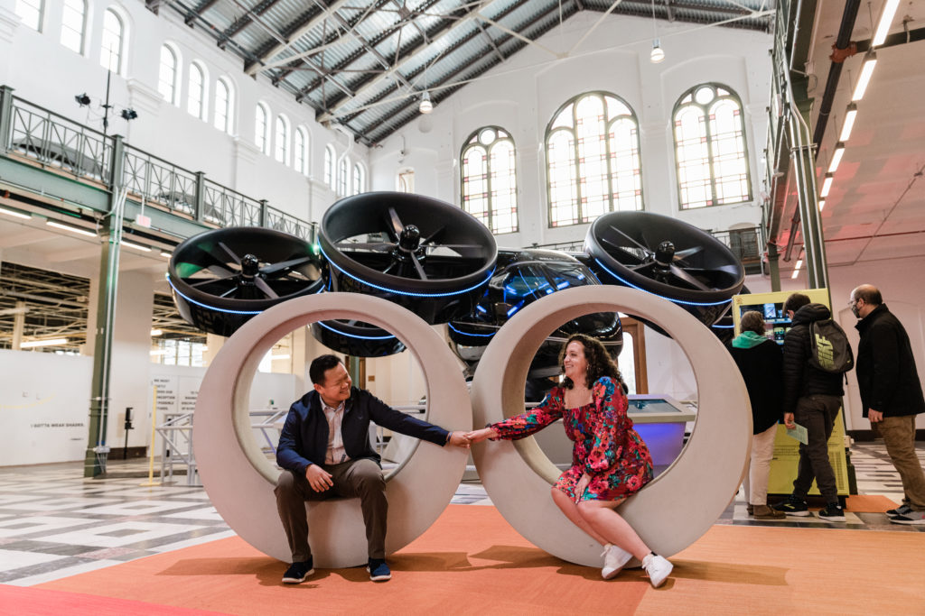 A couple sitting in two round sculptures and holding hands at the Smithsonian Arts and Industries Building