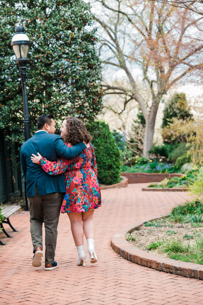 A man and a woman walking in a garden with their arms around each other at the Smithsonian Arts and Industries Building