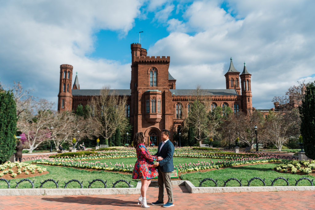 Couple holding hands and looking at each other in front of the Smithsonian Arts and Industries building