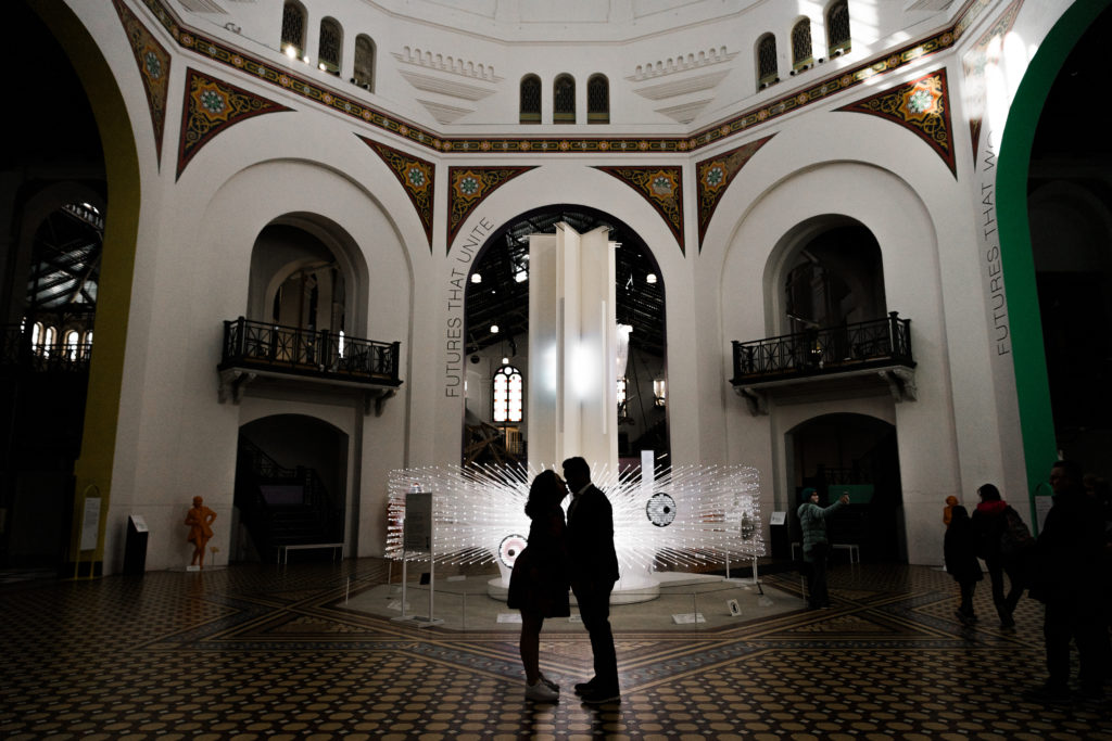 A man and a woman kissing in a dark hall at the Smithsonian Arts and Industries building