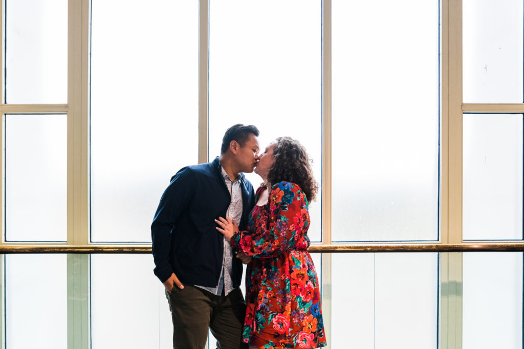 Couple kissing in front of a window at the Smithsonian Arts and Industries Building