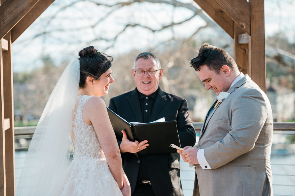 Bride and groom standing with an officiant during a wedding ceremony at the River View at Occoquan