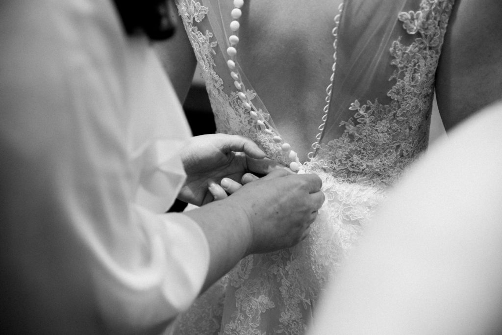 Bride being zipped into her wedding dress