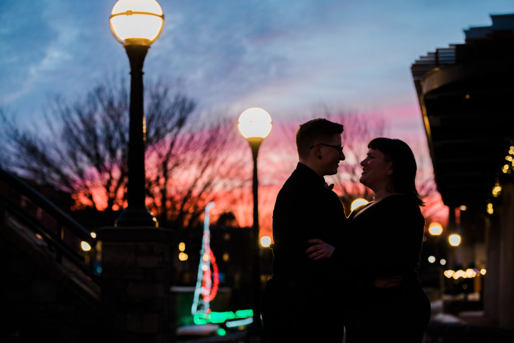 A couple embracing outside with a sunset in the background