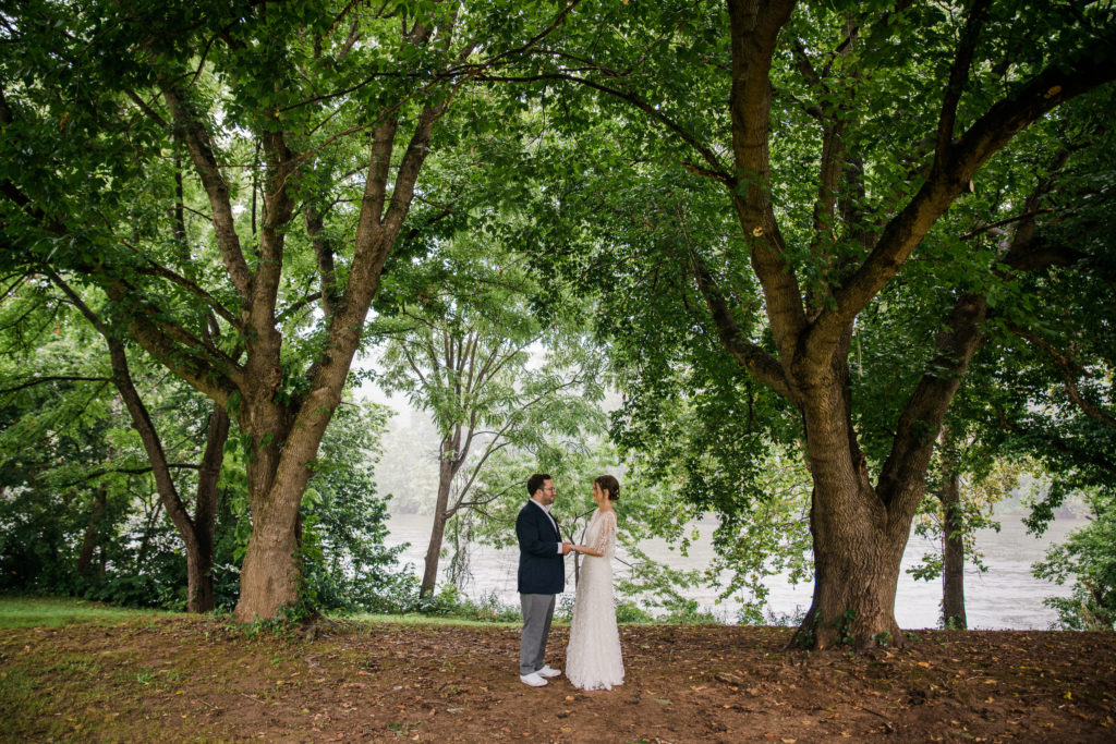 A couple standing together and looking at each other surrounded by trees at Low Water Bridge Campground