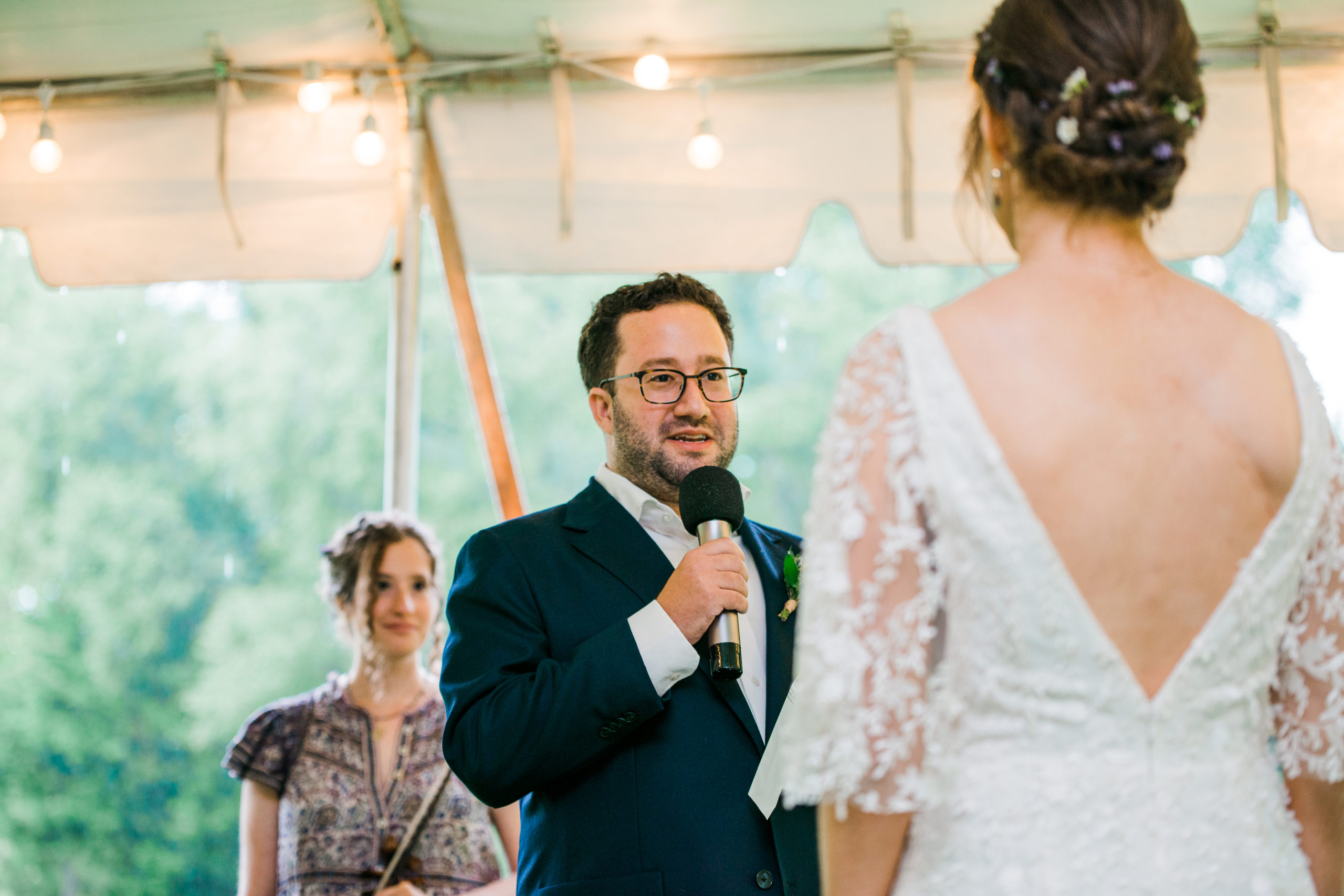 A groom talking into a microphone during a wedding ceremony at Low Water Bridge Campground