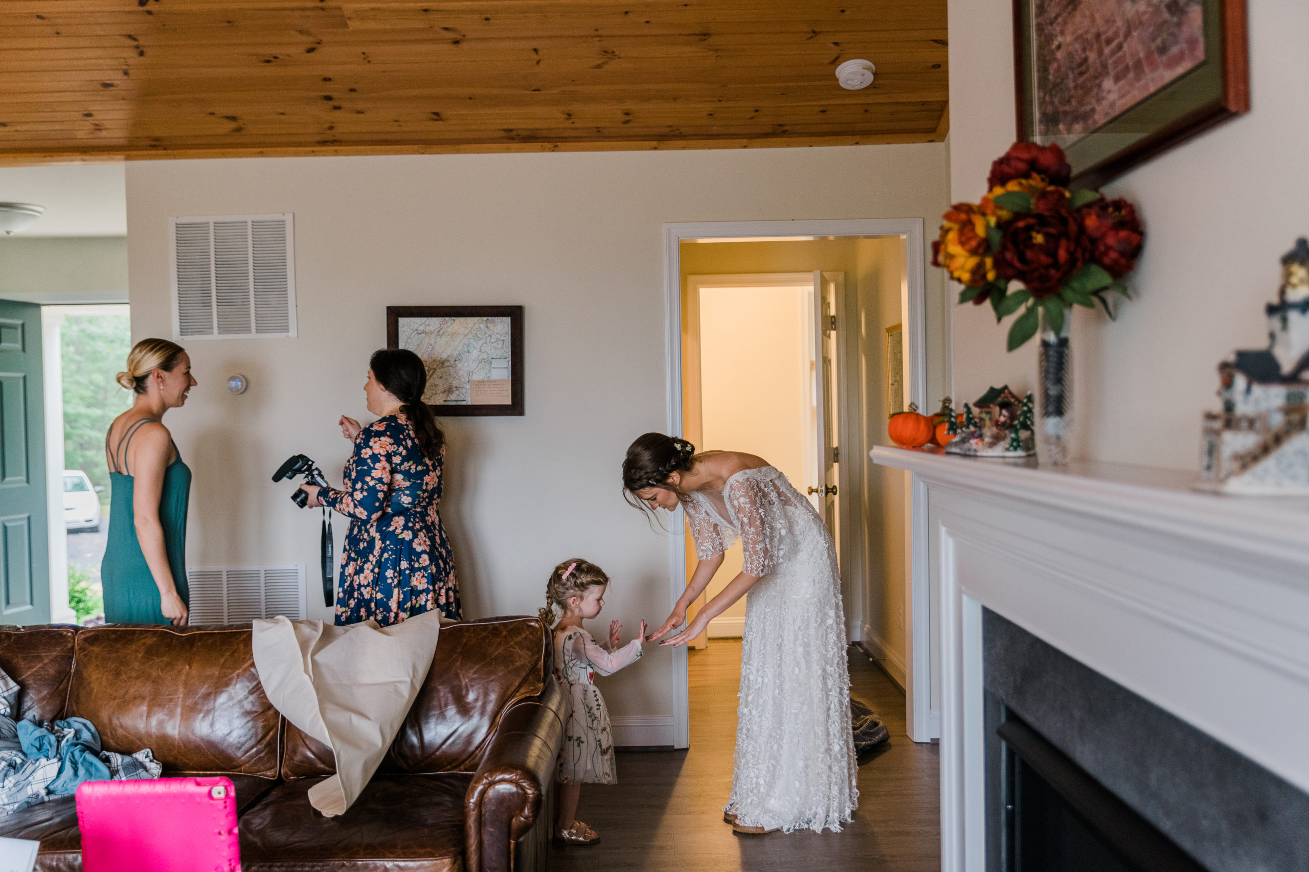 A bride in a white wedding dress bending down to talk to a little girl