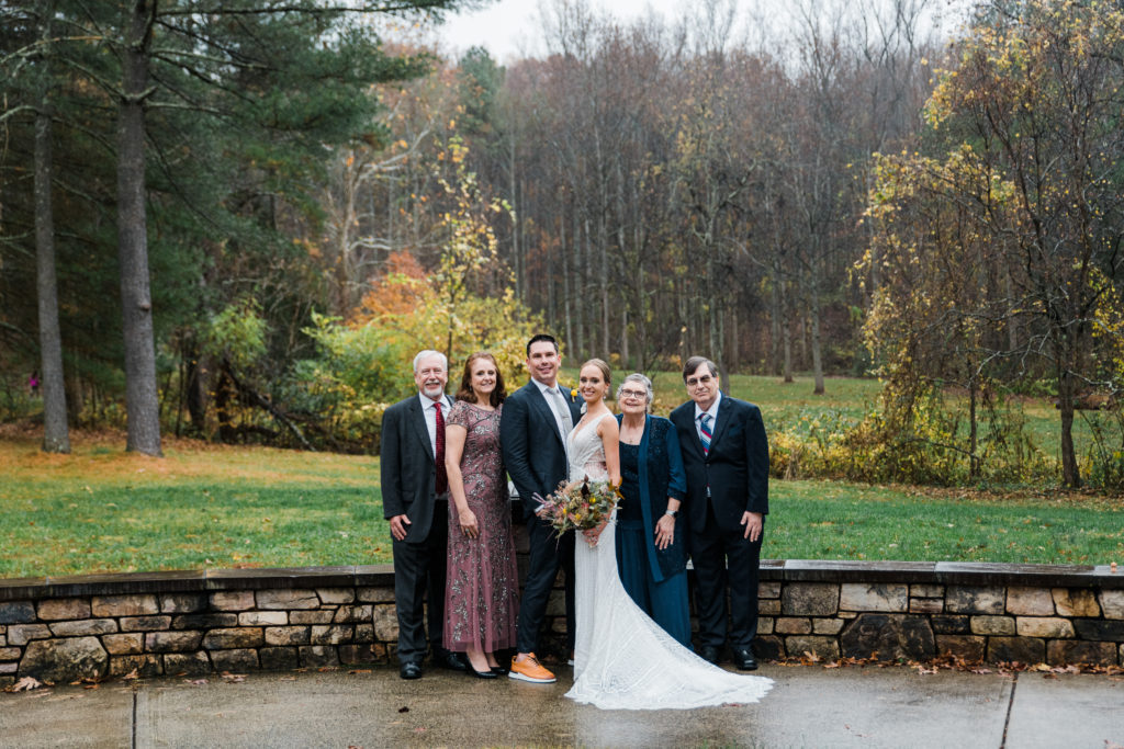 A bride and groom pose outside with their families