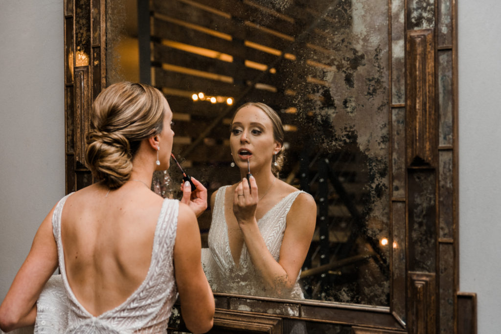 Bride putting on lipstick in a mirror