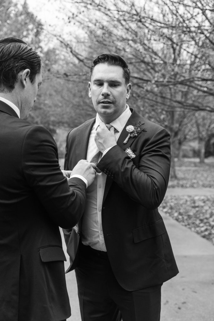 A groom adjusting his tie