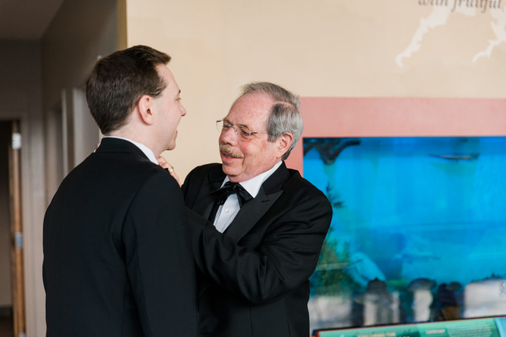 A man helps a groom with his tie
