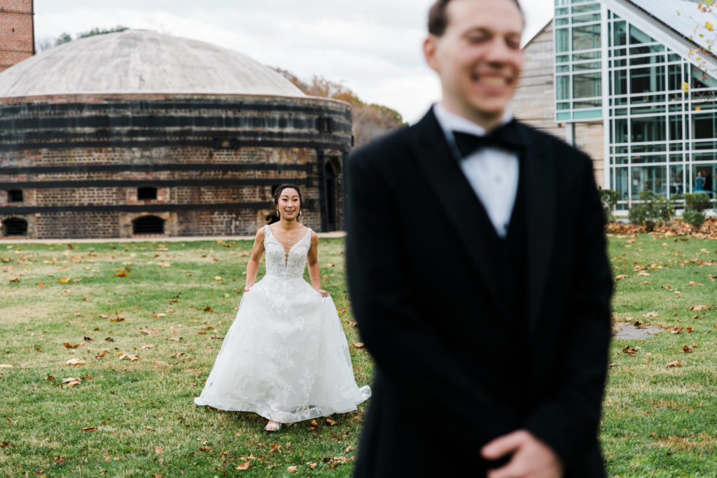 A bride walks up behind a groom to surprise him