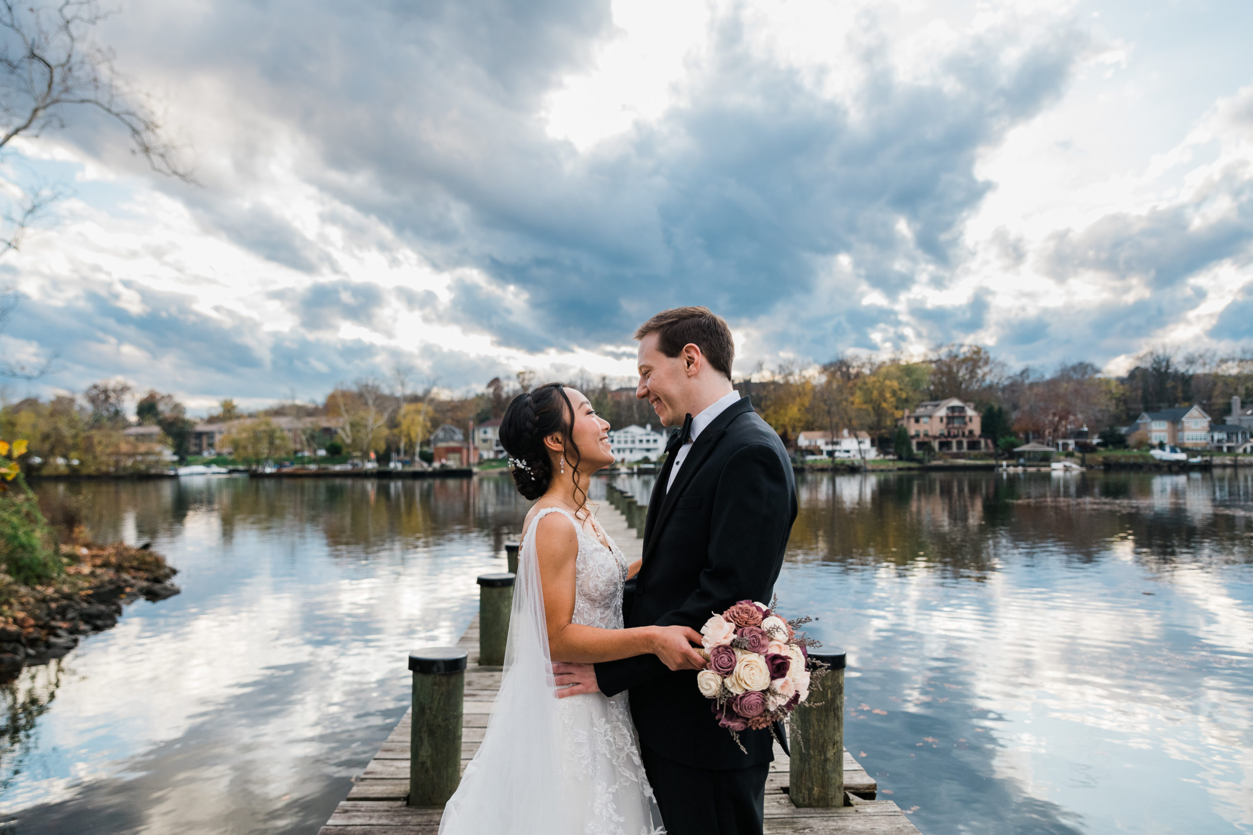 A bride and groom embraces in front of a lake