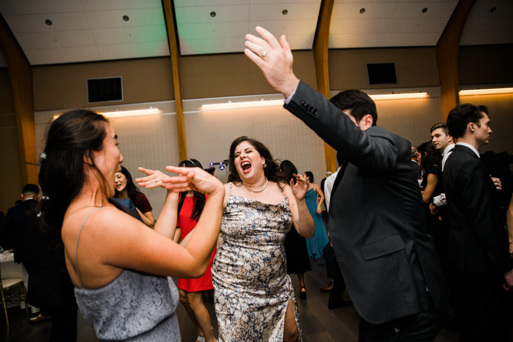 Two women and a man dancing at a wedding reception