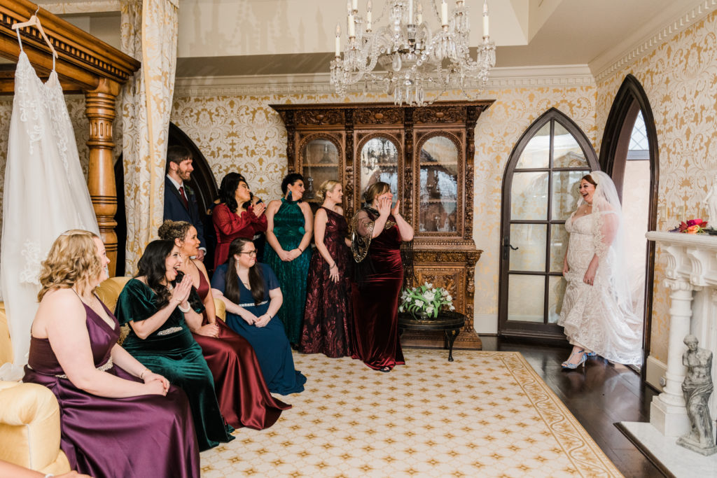 A bride walks into a room filled with women in dresses