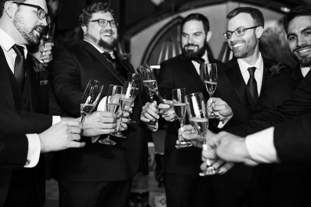 Black and white picture of men in suits clinking wine glasses