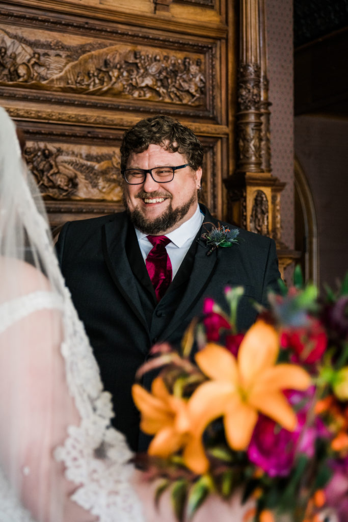 A man smiling as a bride walks up to him
