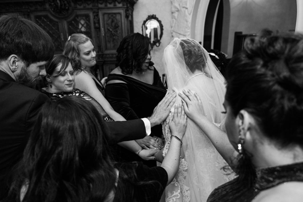 A black and white picture of a group of woman with a bride praying
