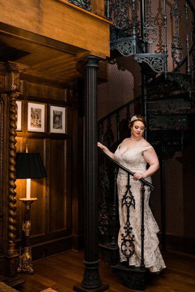 A bride in a white dress posing on a spiral staircase