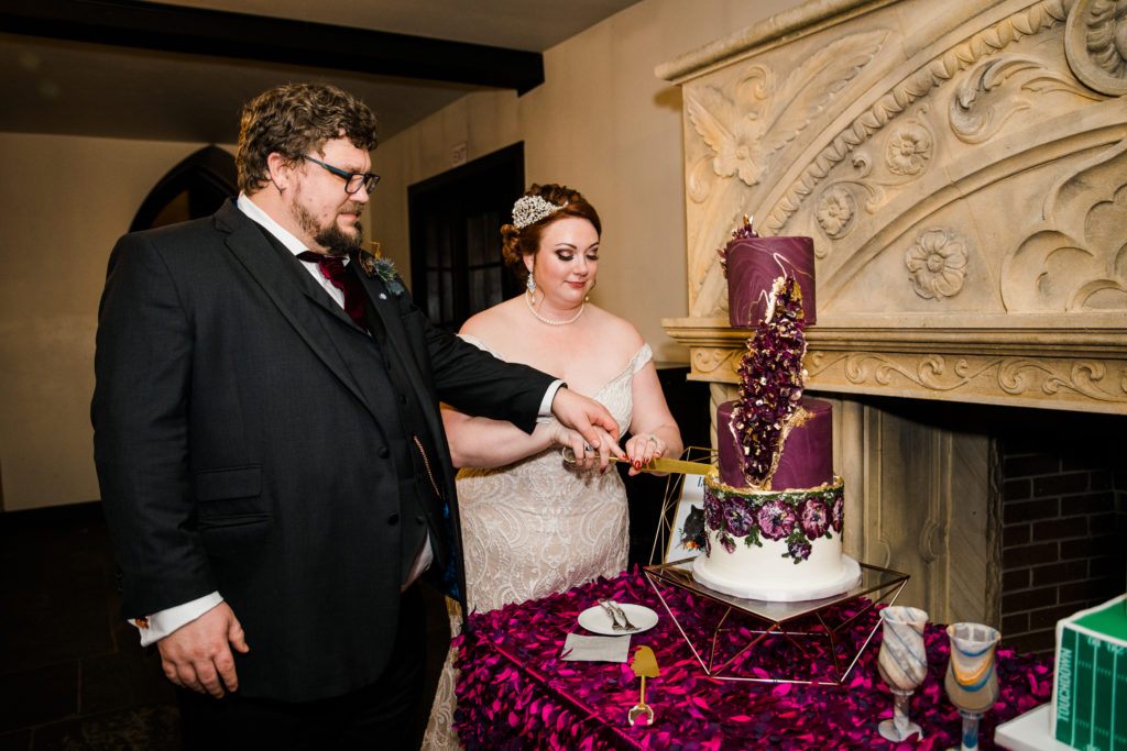A bride and groom hold a  knife to cut a large wedding cake
