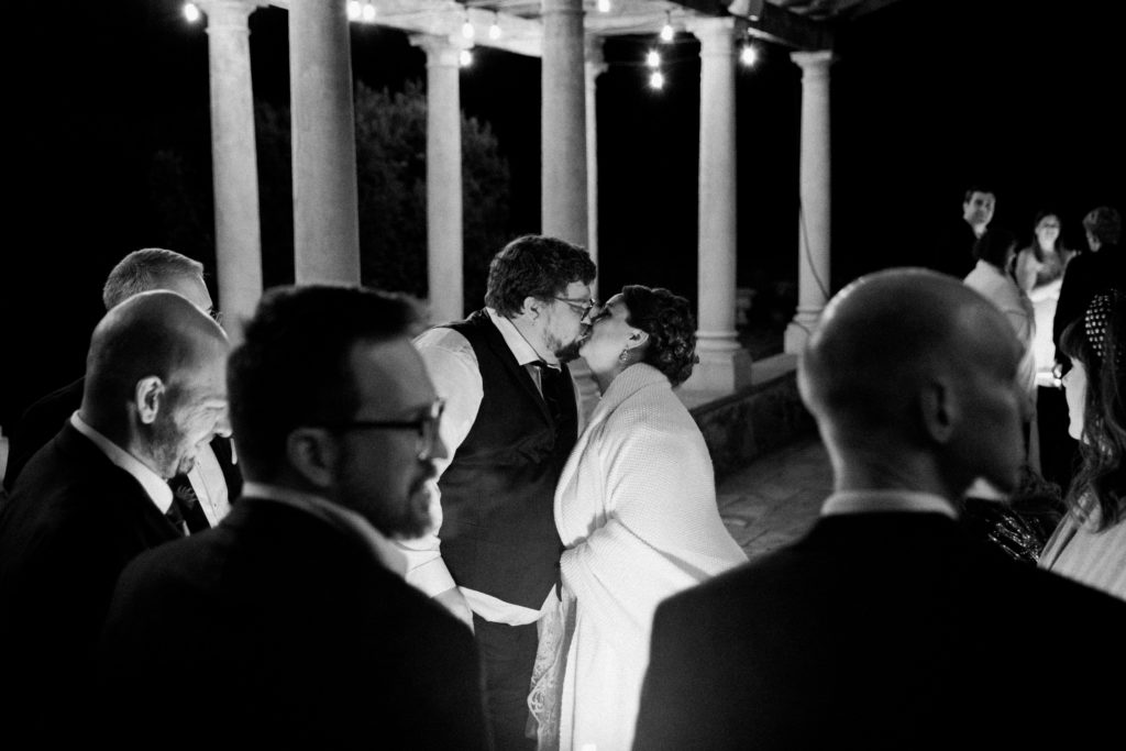 A black and white picture of a bride and groom kissing