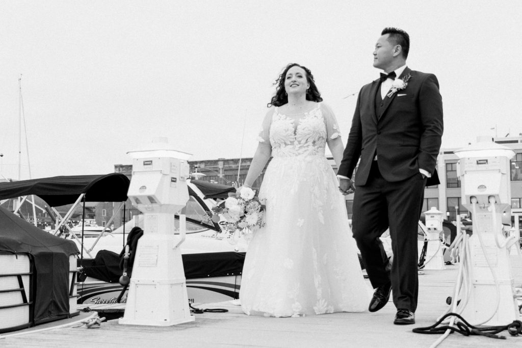 A bride and groom standing on a boat dock
