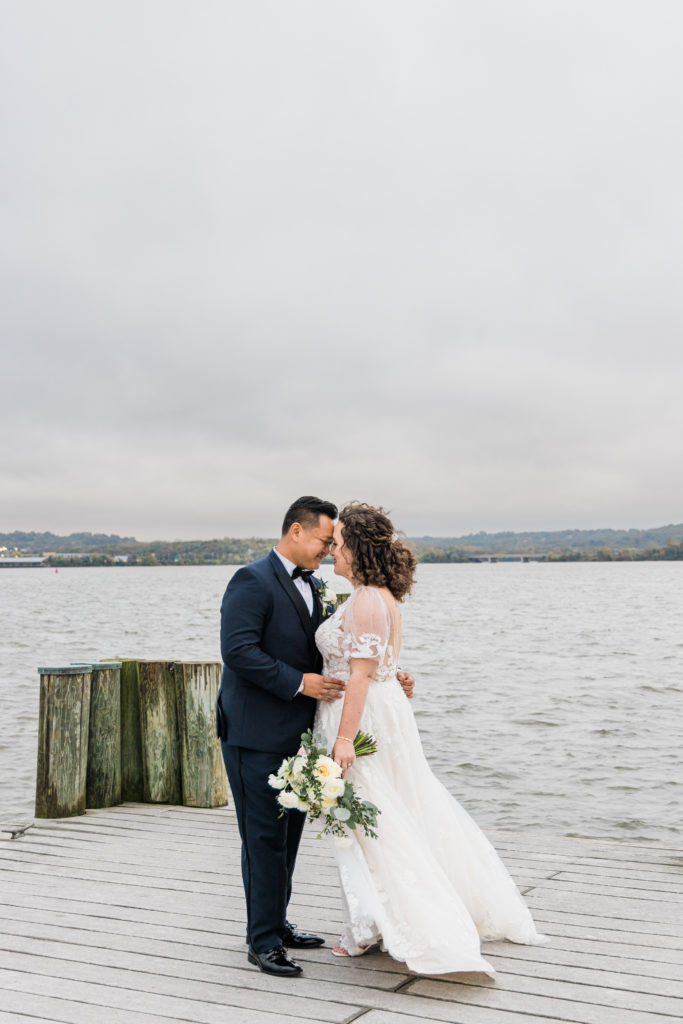 A bride and groom standing on a boat dock