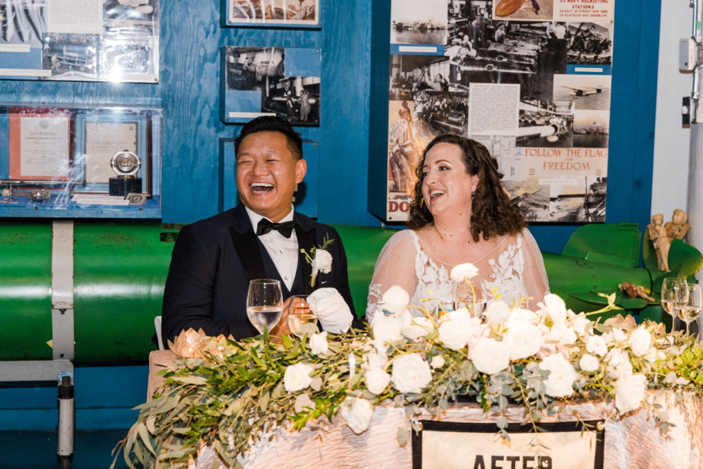 A bride and groom sitting at a table laughing