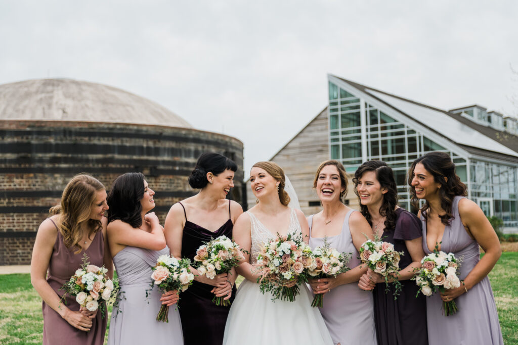 7 women in dresses standing together and laughing