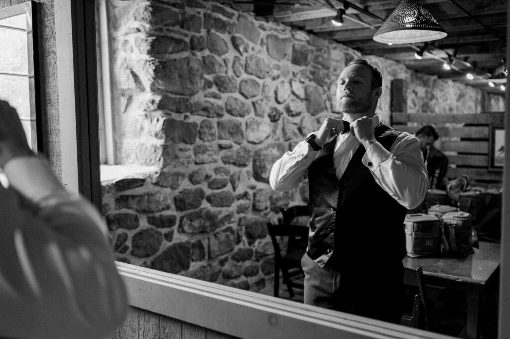 A man looking in a mirror and fixing his tie