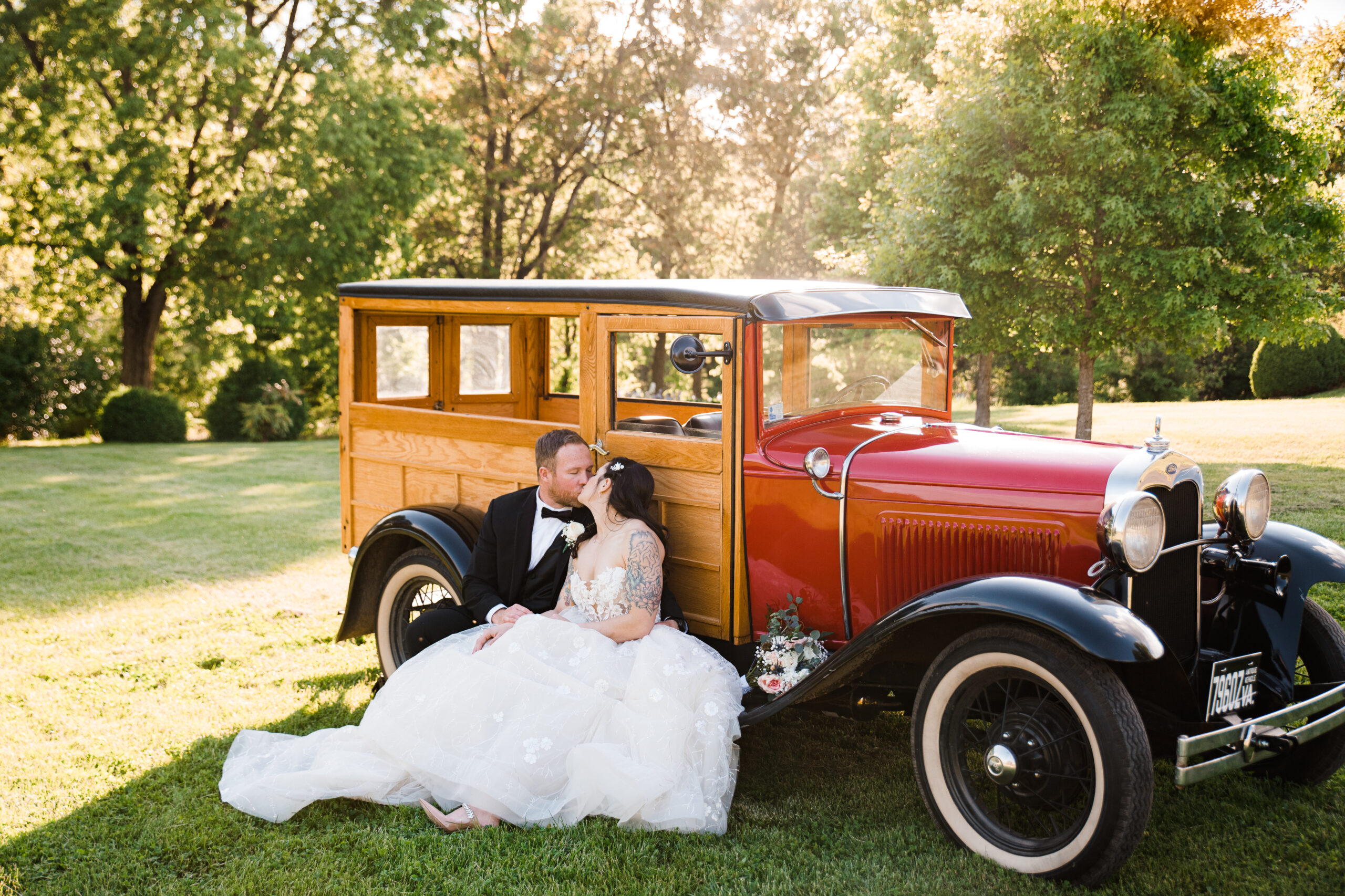 A man and woman sitting in front of a vintage car kissing