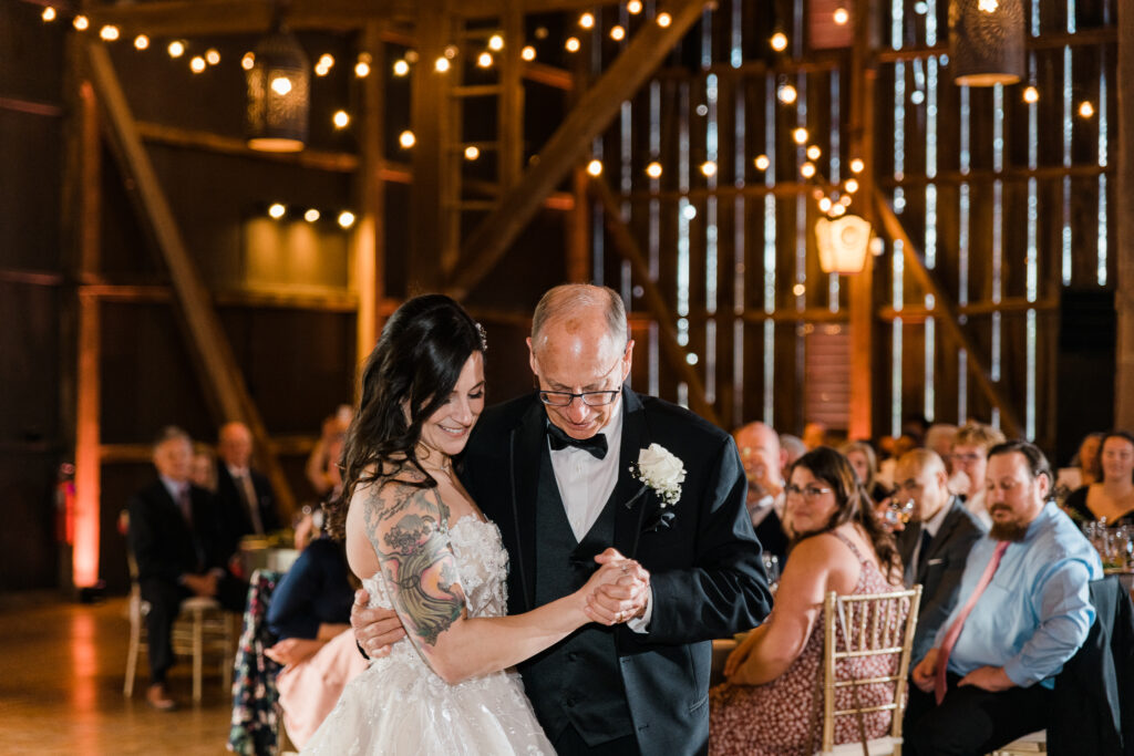 A bride dancing with her father in a reception hall