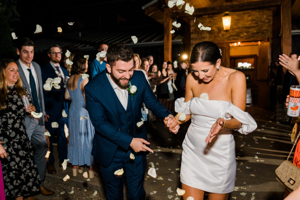 Wedding guests tossing flower petals at a bride and groom